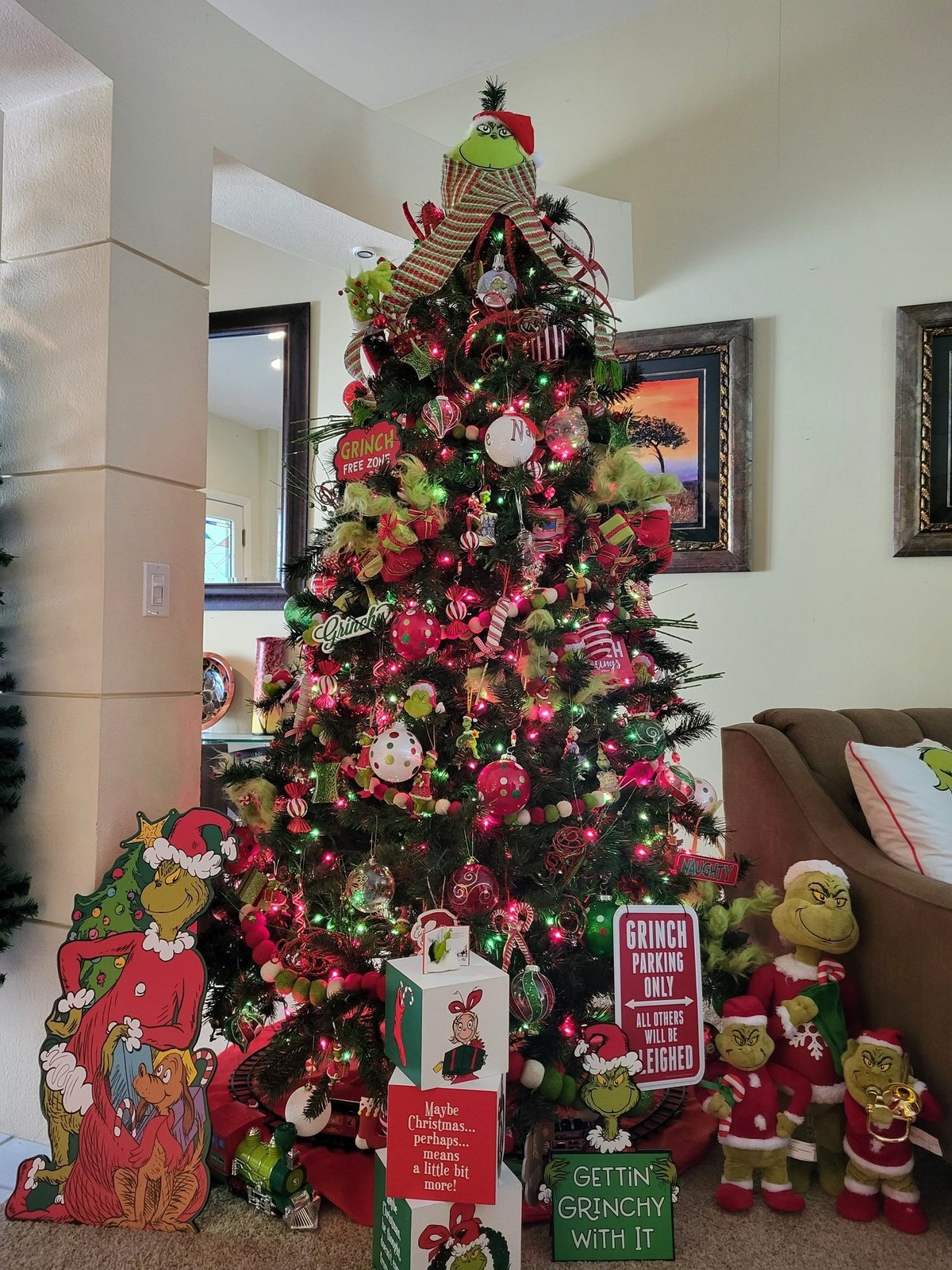 Grinch themed Christmas tree in a living room with green and red decorations