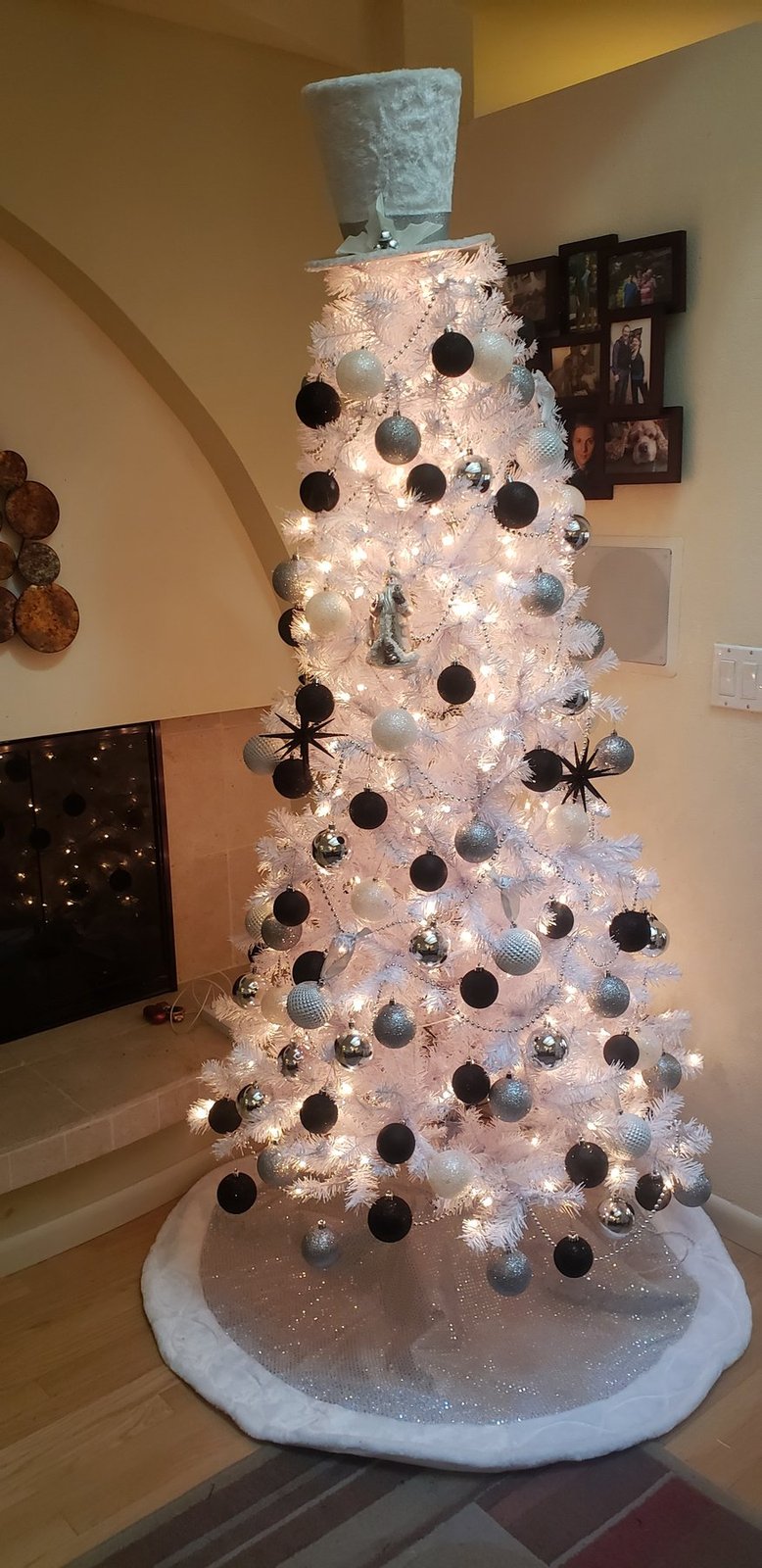 White Christmas tree with black and silver ornaments on a white tree skirt