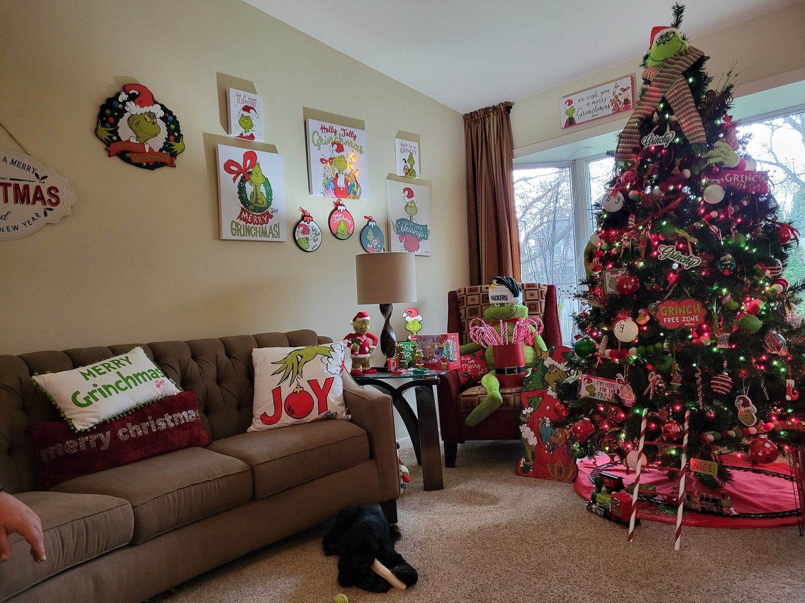 Living room decorated with a Grinch themed tree and holiday pillows