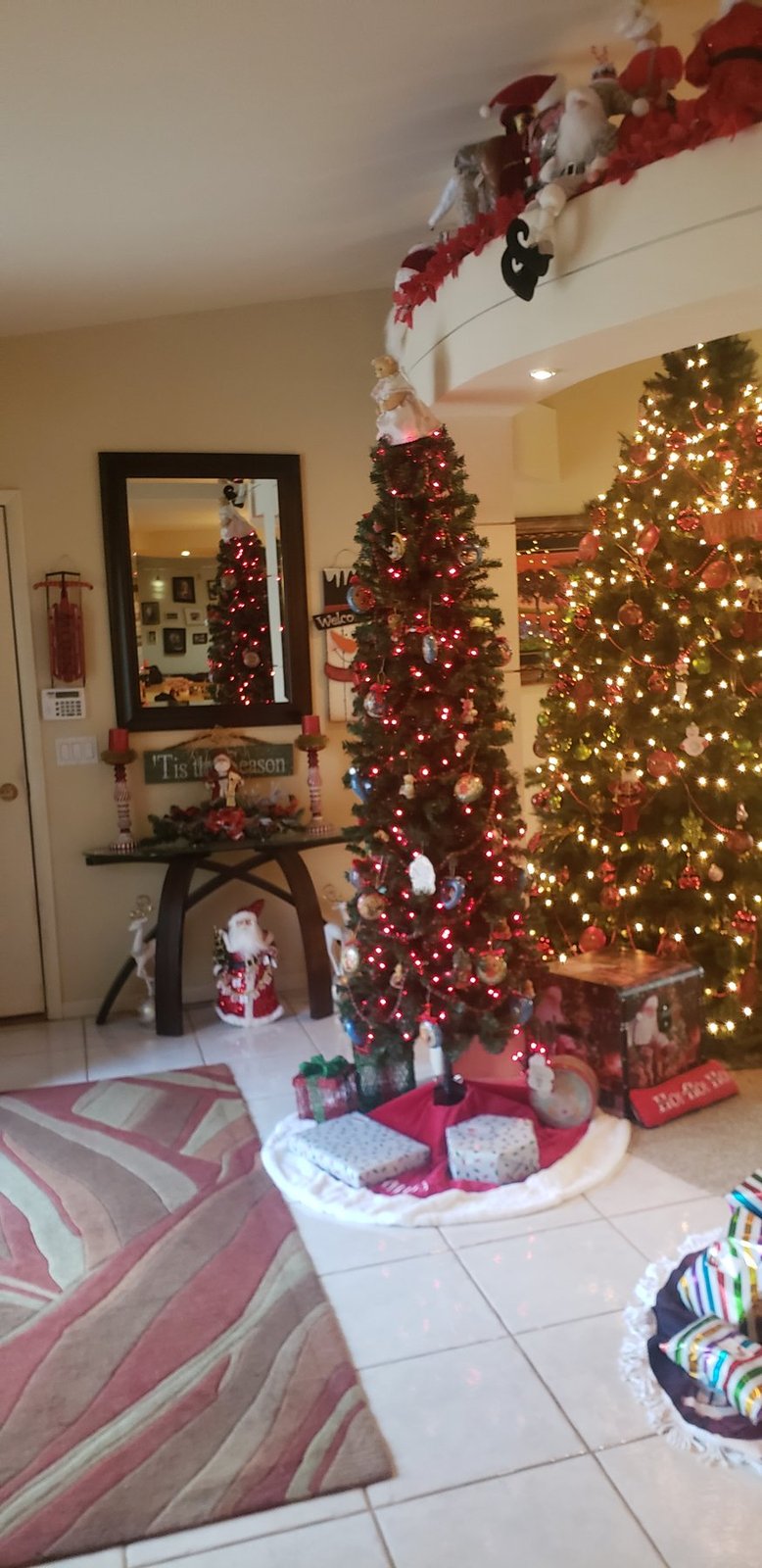 Red and gold Christmas tree in an entry hall beside a mirror