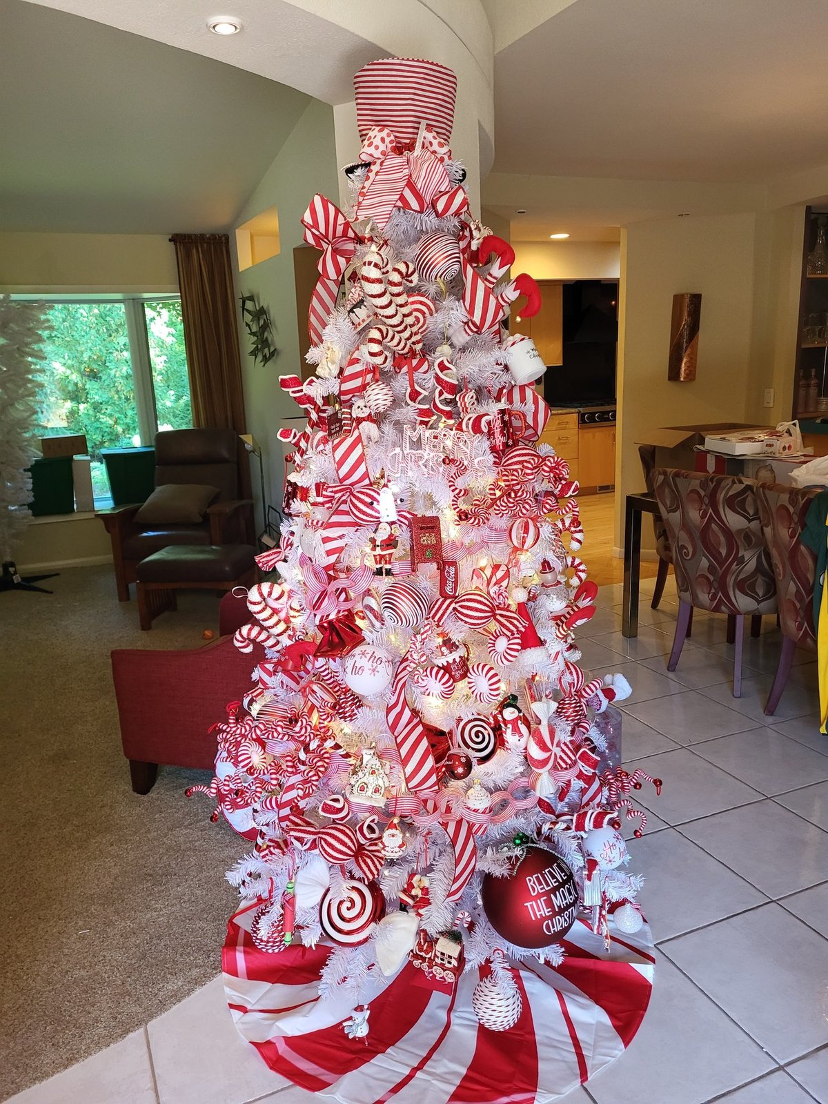 Red and white candy cane themed Christmas tree in a tiled room