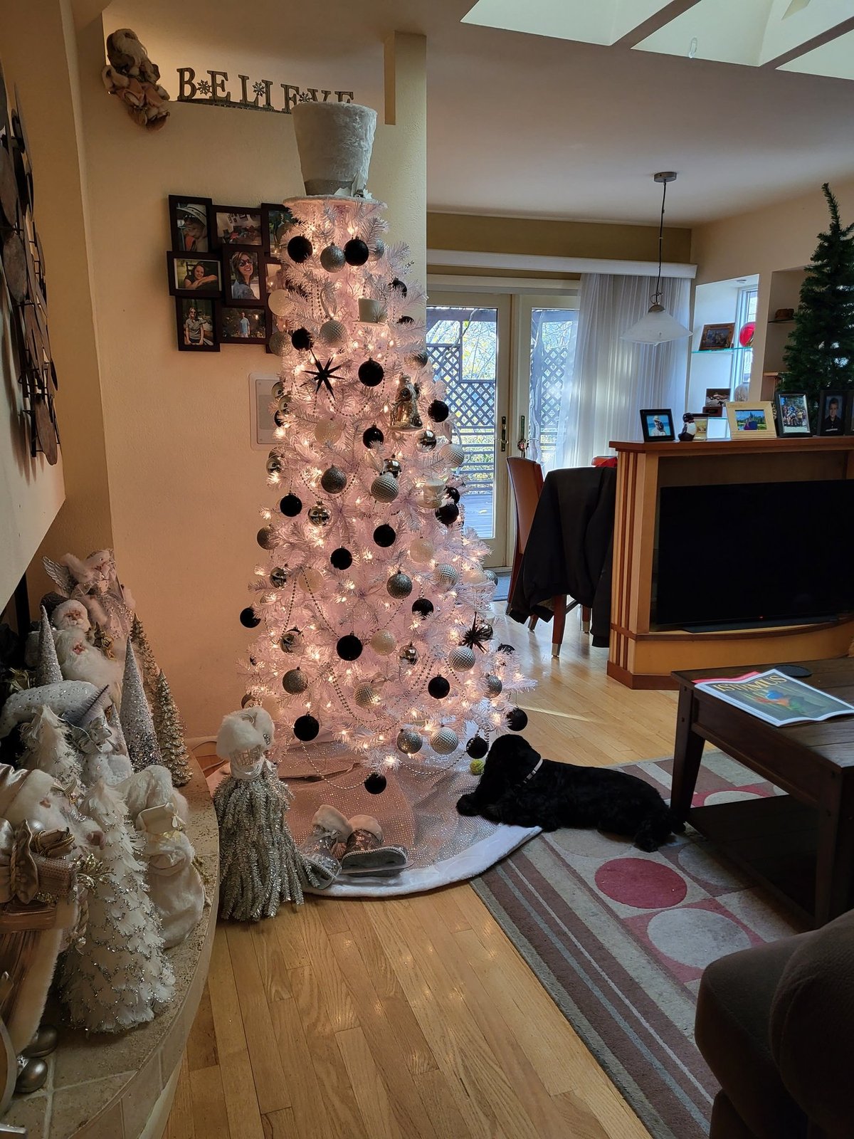 White Christmas tree with black ornaments in an open living area