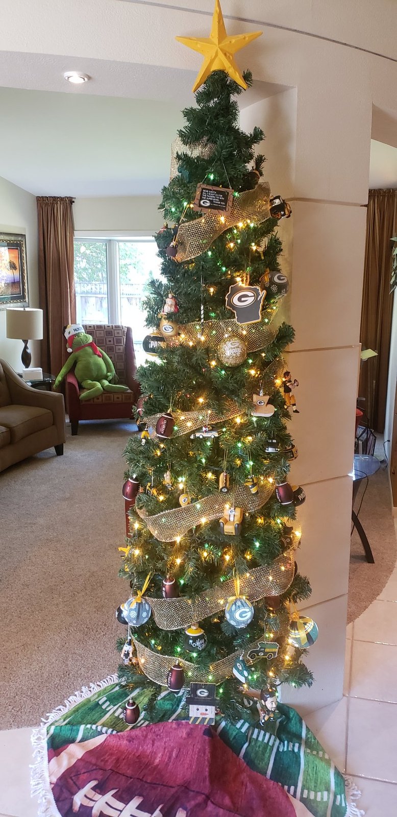 Tall green Christmas tree with a gold star topper in a carpeted living room