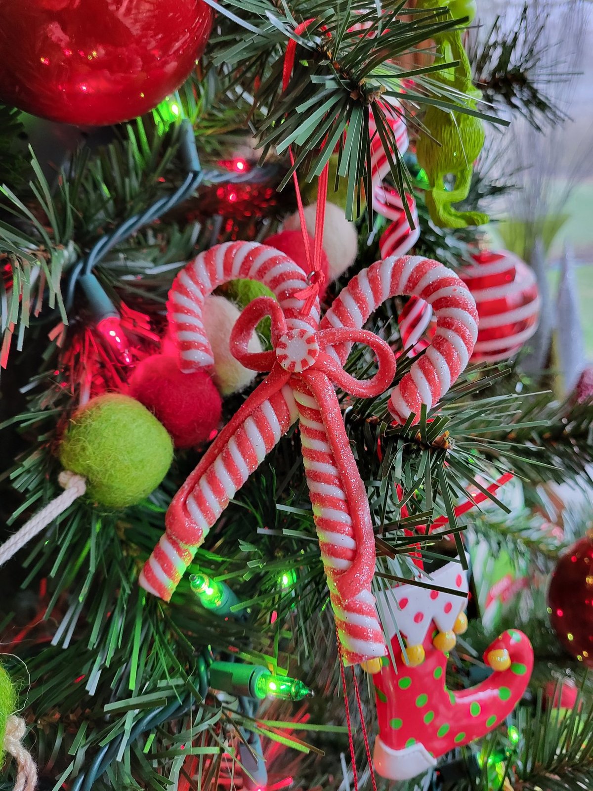 Close view of candy cane ornaments and ribbon on a green tree