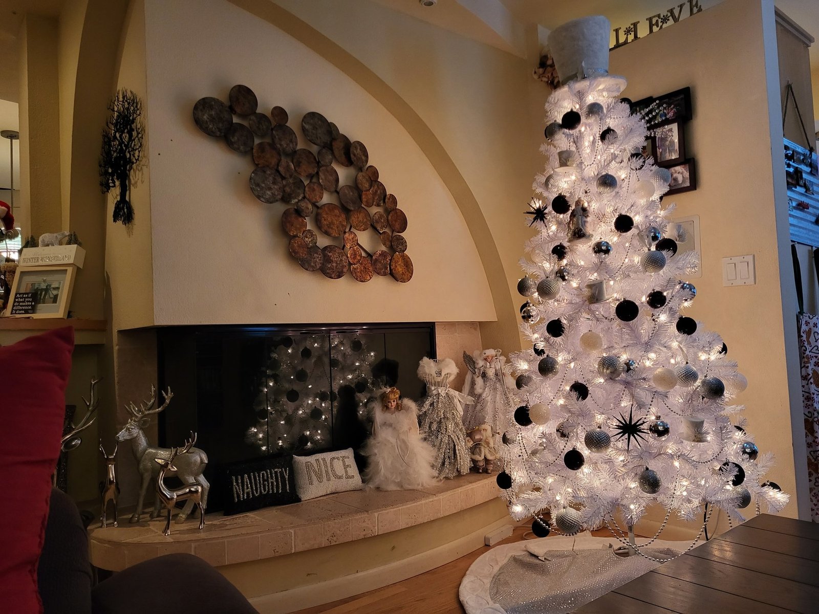 White Christmas tree with black ornaments beside a stone fireplace