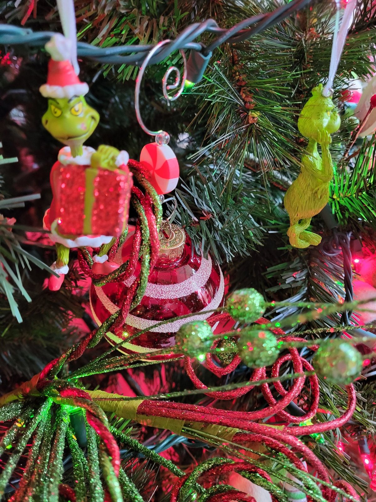 Close view of Grinch ornaments and a wrapped gift on a decorated tree