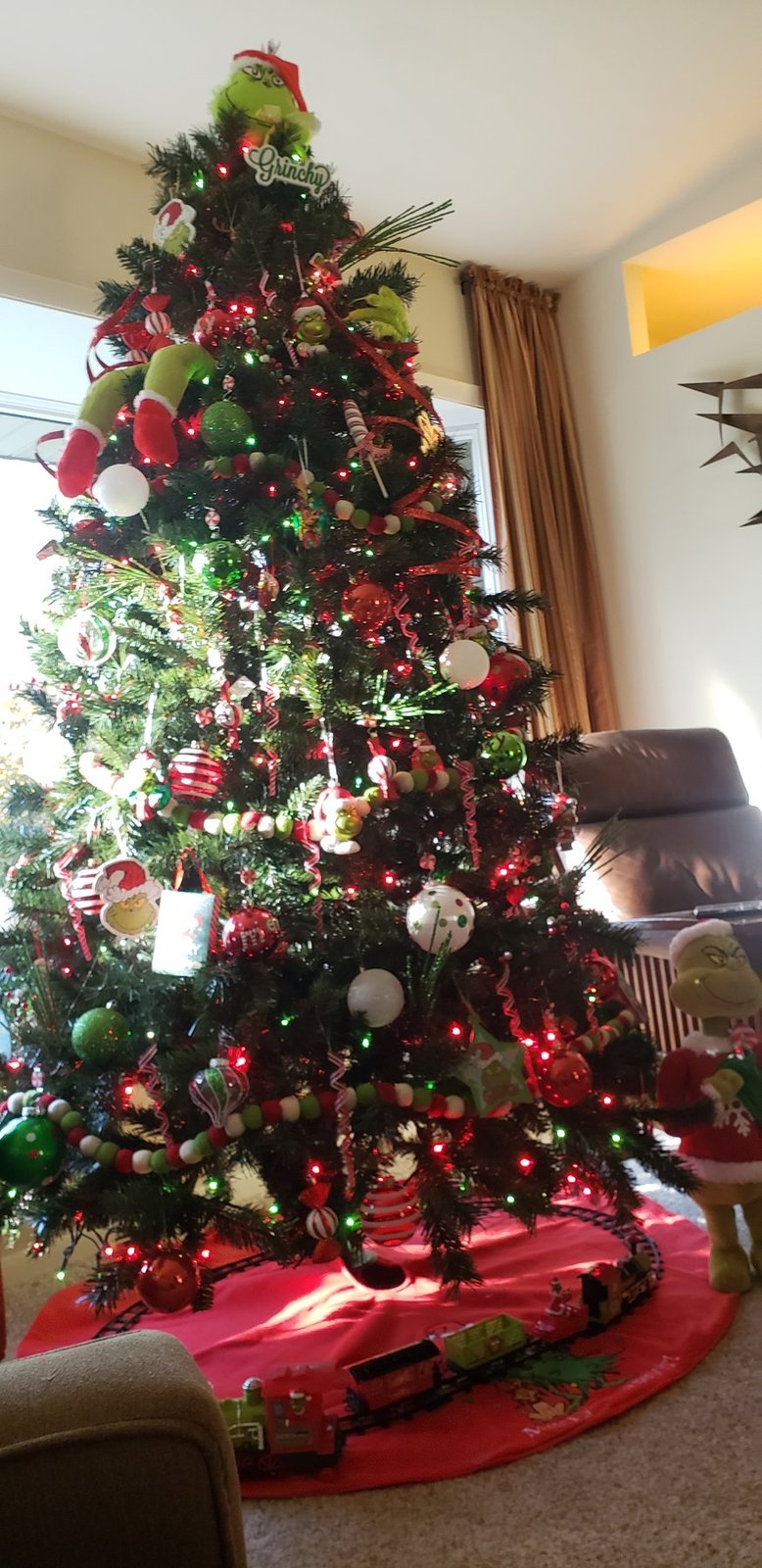 Christmas tree with red and silver ornaments beside a living room chair