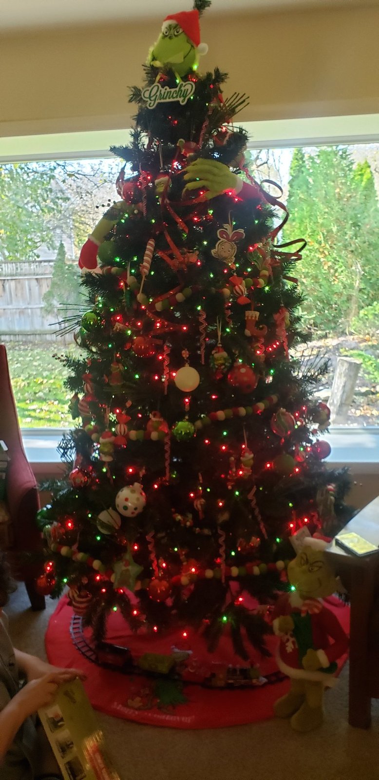 Green Christmas tree with red picks and warm lights in front of a window