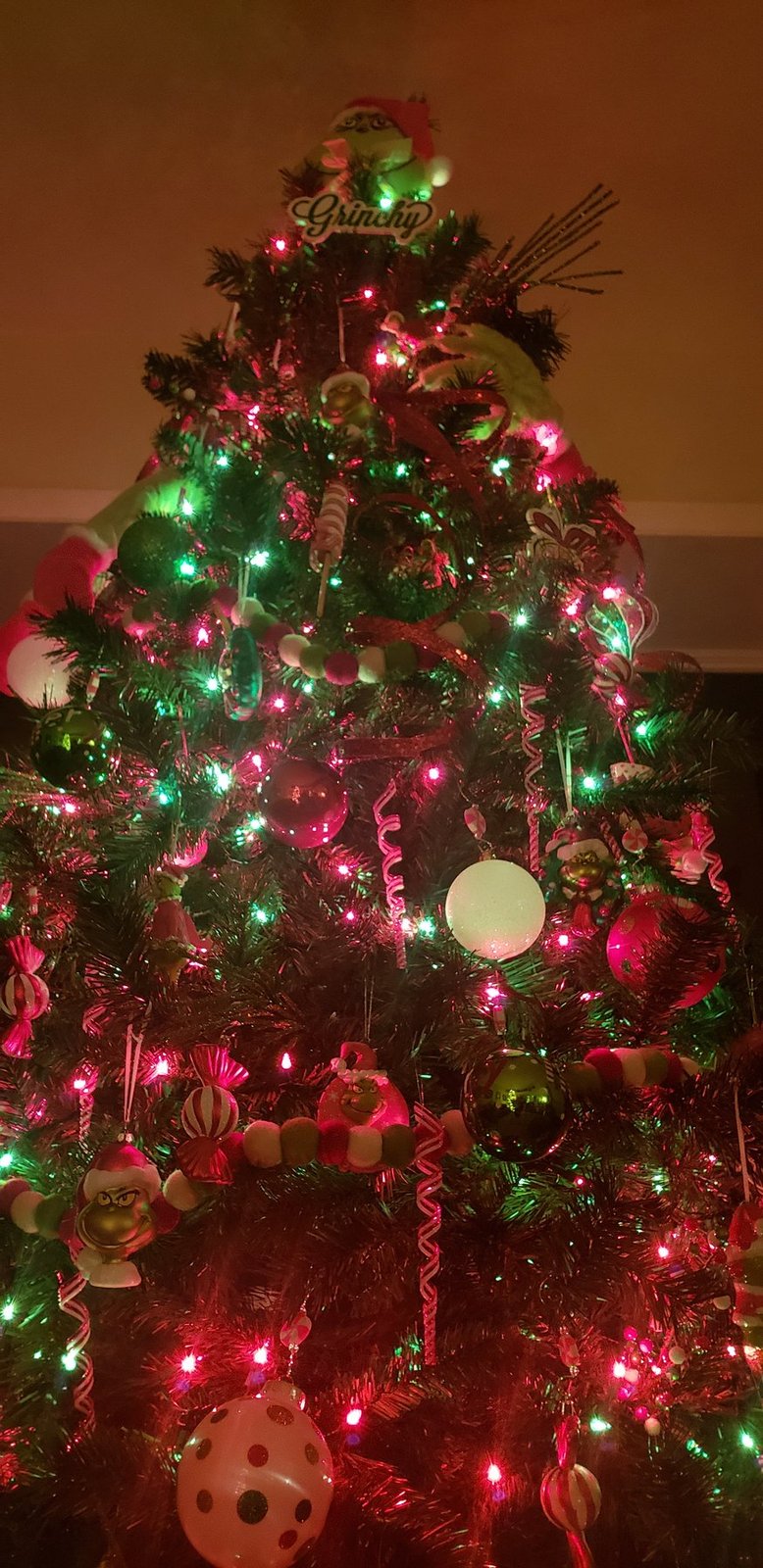Christmas tree lit in red and green with ribbon and layered ornaments
