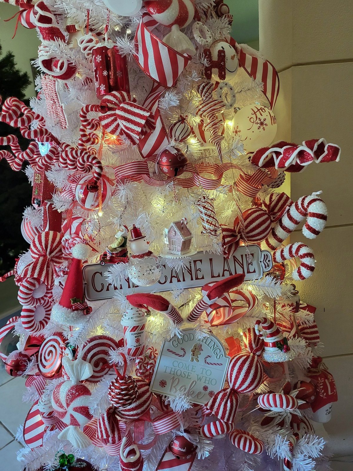 Close view of a candy cane themed tree with a Cane Lane sign and oversized peppermint picks